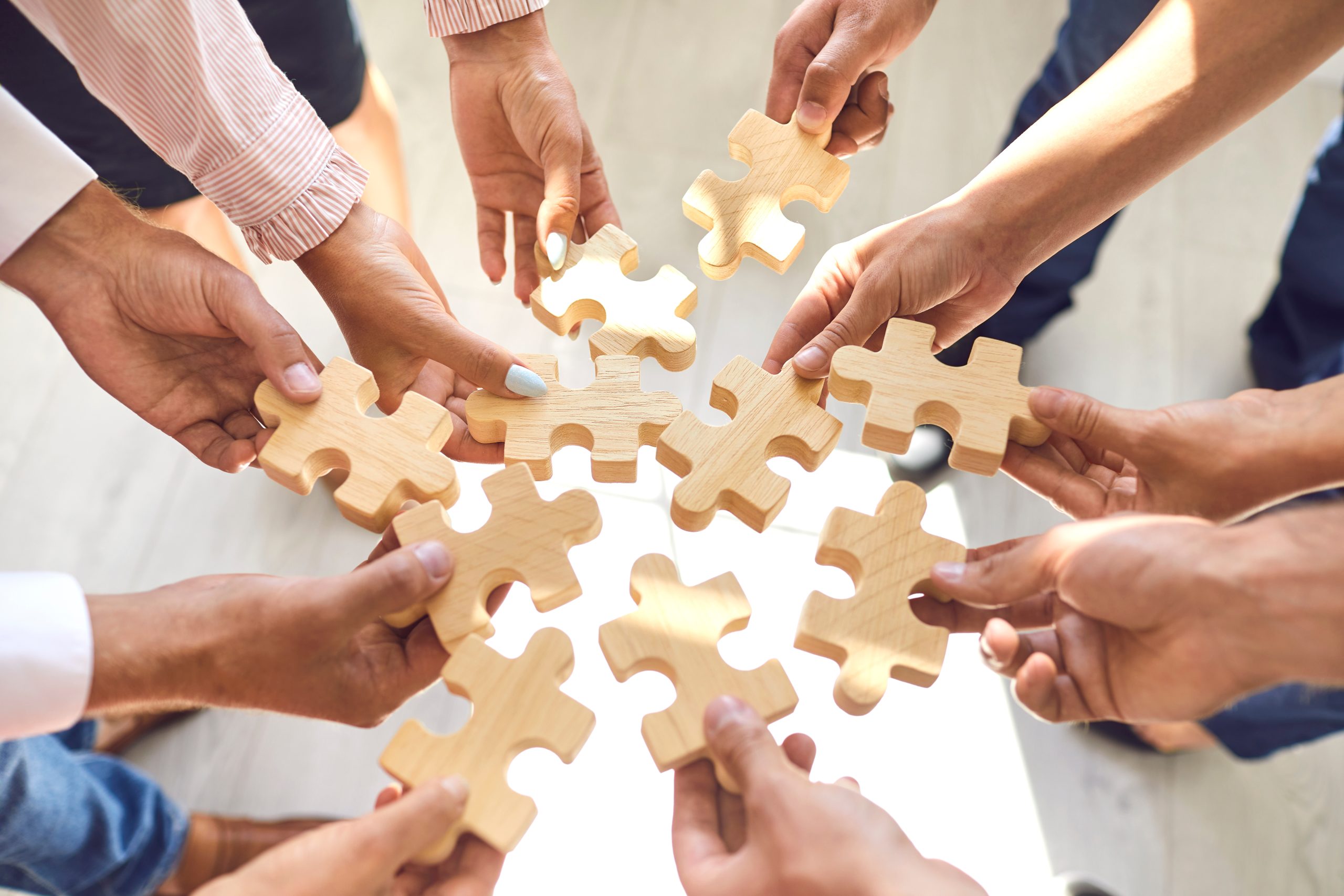 company employees playing game and joining pieces of jigsaw puzzle during team building activity